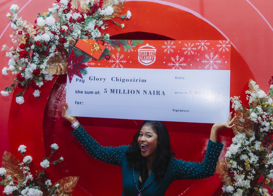 A past Hilda Baci Academy winner holding an oversized ₦5 million cheque